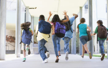 Rear,View,Of,Elementary,School,Pupils,Running,Outside